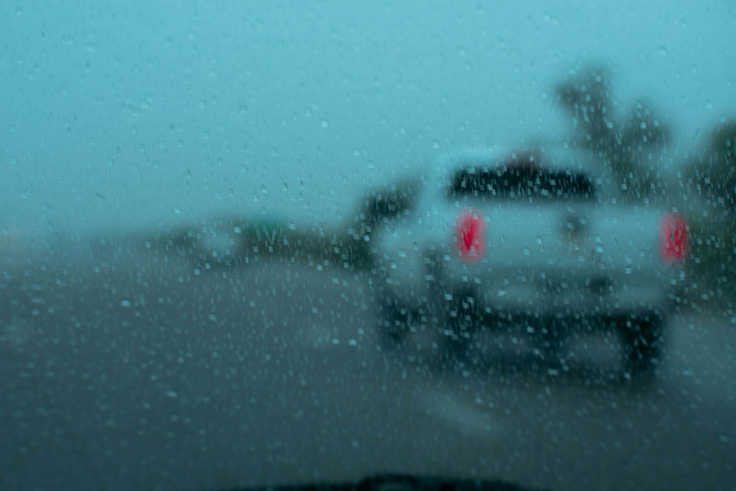 Driving through rain on a wet road at dusk.
